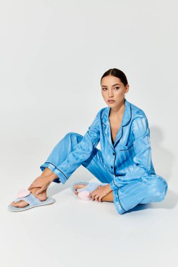 Şık mavi pijama takımı giymiş genç bir kadın evde sakin bir anın tadını çıkarıyor..