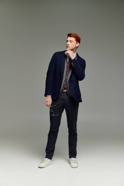 Kızıl saçlı yakışıklı genç bir adam düşünceli bir poz verirken sofistike bir kış görüntüsü sergiliyor..