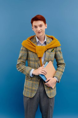 Çarpıcı kızıl saçlı genç bir adam şık kış kıyafetlerini sergilerken kendine güvenen bir duruşu benimsiyor..