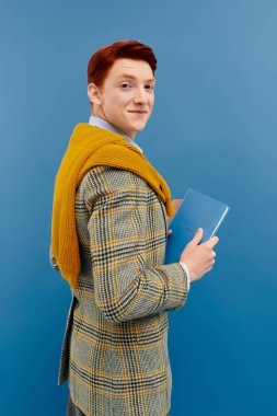 Çarpıcı kızıl saçlı genç bir adam şık bir kış elbisesi içinde, moda anlayışını ön plana çıkarıyor..