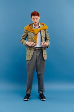 Kızıl saçlı genç bir adam şık katmanlı bir kış görüntüsü sergiliyor, zarafet ve modern tarzı birleştiriyor..