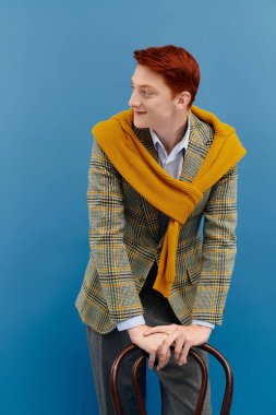 Çarpıcı kızıl saçlı genç bir adam katmanlı bir kış elbisesi içinde şık bir şekilde poz veriyor..