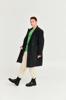 A young man with striking red hair showcases his fashion sense in an elegant winter coat and stylish boots. clipart