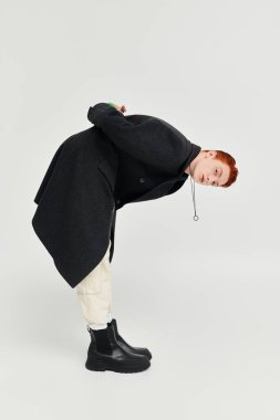 Yakışıklı, kızıl saçlı genç bir adam şık bir kışlık ceketle yaratıcı bir şekilde poz veriyor..