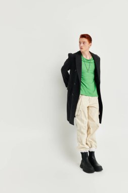 A handsome young man with striking red hair showcases his winter fashion in a studio setting, exuding confidence. clipart