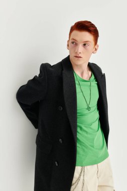 Kendine güvenen kızıl saçlı genç bir adam şık bir kışlık ceketle moda anlayışını sergiliyor..