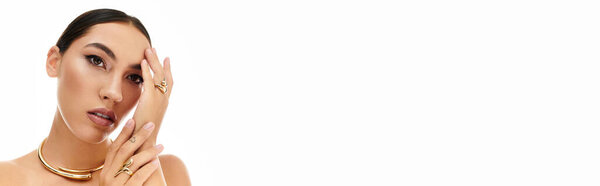 A young woman gracefully highlights her stunning jewelry in a chic and stylish pose.