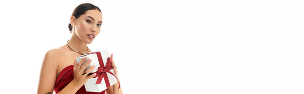 Радостная молодая женщина демонстрирует тщательно завернутый подарок, излучающий счастье и очарование.