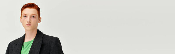 A young man with vibrant red hair effortlessly captures attention in his elegant winter coat.