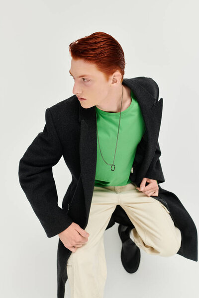 Молодой человек с яркими рыжими волосами демонстрирует моду в шикарном зимнем пальто, источая уверенность и стиль.