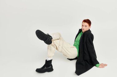 Kızıl saçlı yakışıklı bir adam stüdyoda moda sergiliyor. Zarafet ve kendine güven gösteriyor..