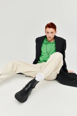 Şık bir adam kışlık montuyla yaratıcı bir şekilde poz verir, moda tercihlerini ve benzersiz tarzını ön plana çıkarır..