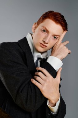 Kendine güvenen kızıl saçlı genç bir adam, dalgın bir poz verirken kış modasını sergiliyor..