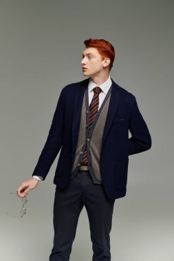 A handsome young man with red hair showcases a layered winter outfit, exuding confidence in a studio. clipart