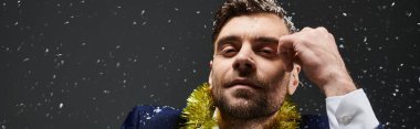 Düşünceli bir yüzü olan şık bir genç adam kar yağarken neşeli bir anın tadını çıkarır..