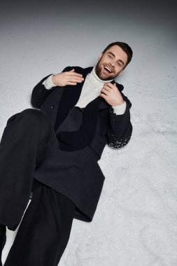 Genç bir adam kışın etrafı karla çevriliyken neşeyle gülüyor..