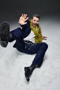 Resmi giyinmiş neşeli bir genç adam neşeli bir şekilde karda oynuyor..