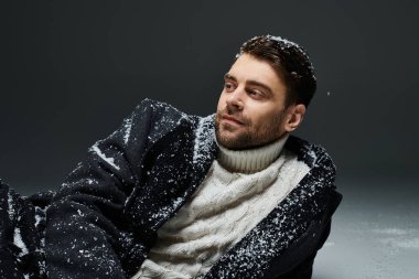 Tarz sahibi genç bir adam, soğuk bir günde yumuşak kar taneleri arasında huzur dolu bir anın tadını çıkarır.