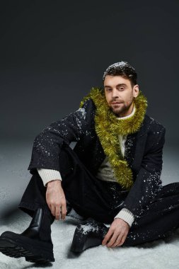 Yakışıklı bir genç adam şık bir elbise içinde poz veriyor. Kış süslemeleri ve kar ile süslenmiş..