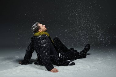 A young man relaxes in the snow, watching snowflakes gently fall around him. clipart