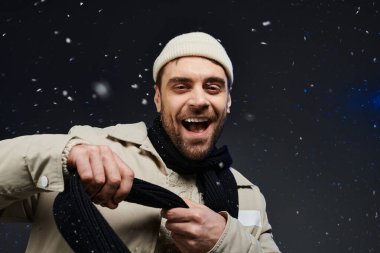 Genç adam sevinçle ışıldıyor, kar tanelerinin arasında rahat bir eşarba sarılı..