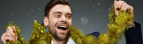 A young man with a big smile enjoys the festive atmosphere while holding tinsel.