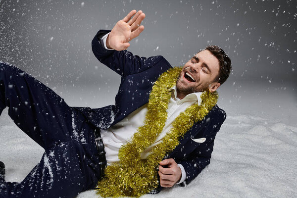 Стильный молодой человек в формальной одежде наслаждается праздничным духом с веселой улыбкой.