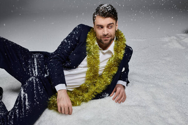 Красивый молодой человек наслаждается игривым моментом в снегу, одетый в официальный наряд.