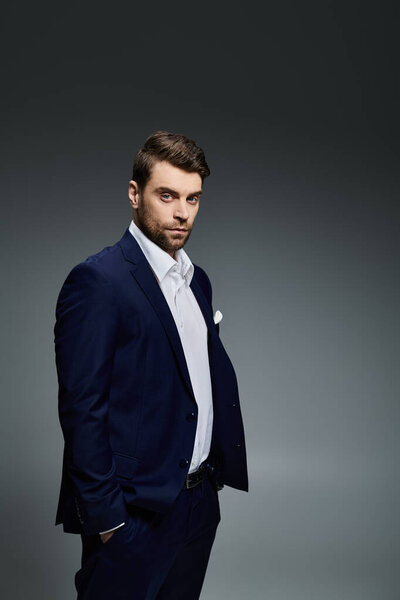 A handsome young man stands confidently in a well fitted suit, showcasing a striking presence.
