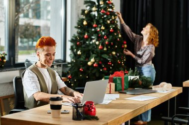 Genç profesyoneller ofis çalışma alanlarının keyfini çıkarırken neşeli bir tatil süslemesi yapıyorlar.