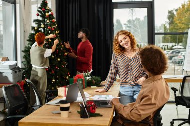 Neşeli bir grup işçi Noel ağacını süslerken bayram şenliklerine katılıyor.