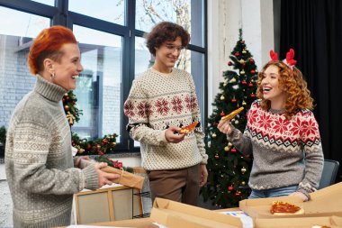 İş arkadaşları pizza ve kahkahaları paylaşırken aynı zamanda işte neşeli bir Noel kutlaması yapıyorlar..