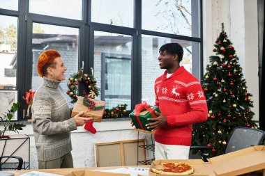 Two coworkers exchange gifts during a cheerful Christmas celebration in their office. clipart