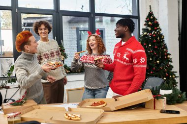 Şenlikli iş arkadaşları, neşeli ofislerinde Noel 'i kutlarken pizza ve kahkahaların tadını çıkarıyorlar..