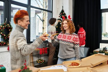 İş arkadaşları Noel 'i süslü bir ofiste kutlarken pizzayı ve kahkahayı paylaşıyorlar..