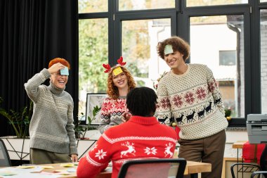 Parlak giyimli iş arkadaşları ofiste neşeli bir bayram kutlaması yapıyorlar..
