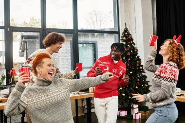 A group of cheerful coworkers enjoys a festive atmosphere while celebrating Christmas at work. clipart