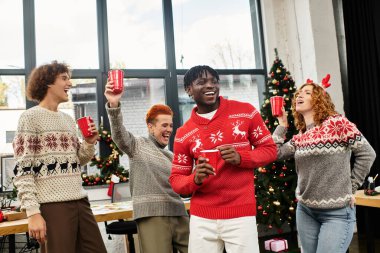 A lively group of coworkers enjoys a Christmas celebration with drinks and cheerful attire. clipart