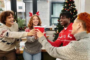 Bir grup genç iş arkadaşı Noel boyunca kutlama içkileri içerken kahkaha ve neşe paylaşıyor..