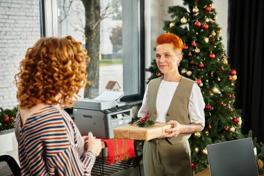 Coworkers exchange gifts and celebrate Christmas joyfully in a decorated office space. clipart