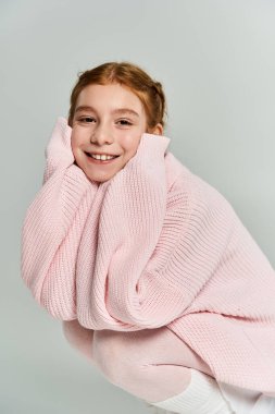 A joyful girl enjoys winter wearing a soft pink sweater, radiating warmth and happiness. clipart