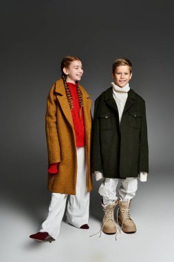 Büyük boy kışlık palto ve kalın botlar giyen iki çocuk eğlenceli bir karlı maceraya hazır..