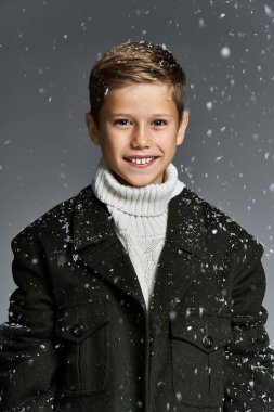 A young boy with a bright smile experiences the joy of winter in cozy clothing with falling snow. clipart