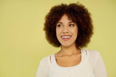 Genç siyah bir kadın, parlak sarı bir arka plana karşı duygularını ifade etmek için iç çamaşırlarıyla güvenle ayakta duruyor..