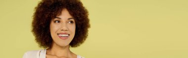 A young Black woman confidently poses in her underwear against a bright yellow background. clipart