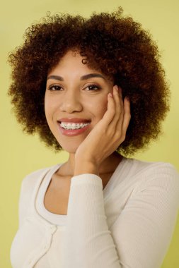 A young Black woman with curly hair joyfully poses in her underwear against a yellow background. clipart