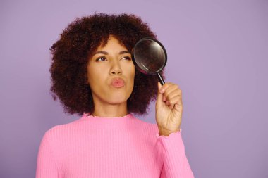 A young woman with curly hair poses thoughtfully, showcasing her emotions against a purple background. clipart