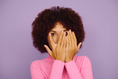 Pembe elbiseli genç bir Afrikalı Amerikalı kadın, bir dizi duygu sergiliyor ve yüzünü neşeyle örtüyor..