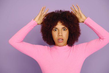 Pembeli genç kadın, canlı mor bir arkaplanda poz verirken şaşkınlığını gösterir..