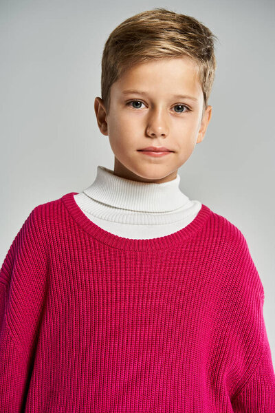 A young boy models a vibrant pink sweater and white turtleneck, exuding warmth and charm.